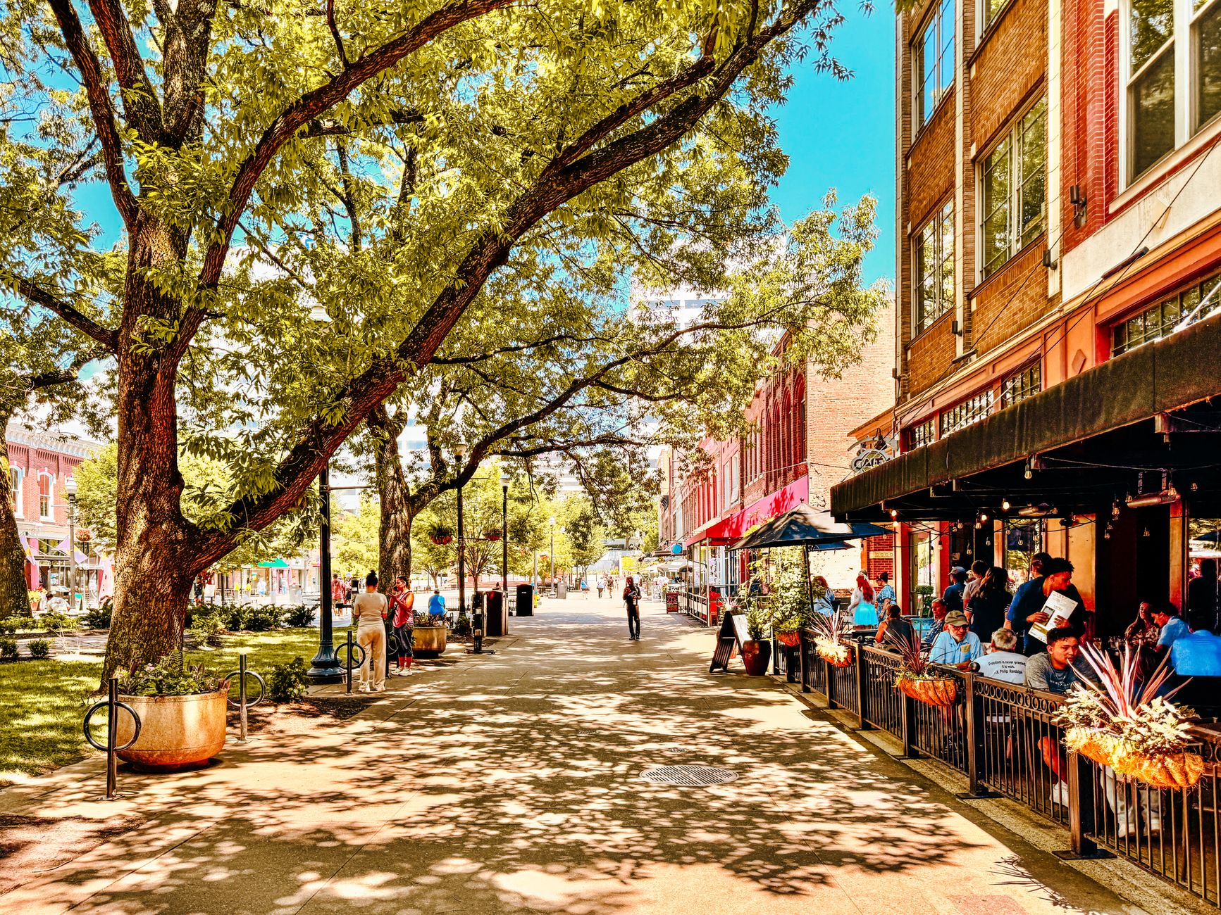 Historic brick buildings and tree-lined streets in Medford Square, Massachusetts, with a mix of classic New England architecture under a clear sky.