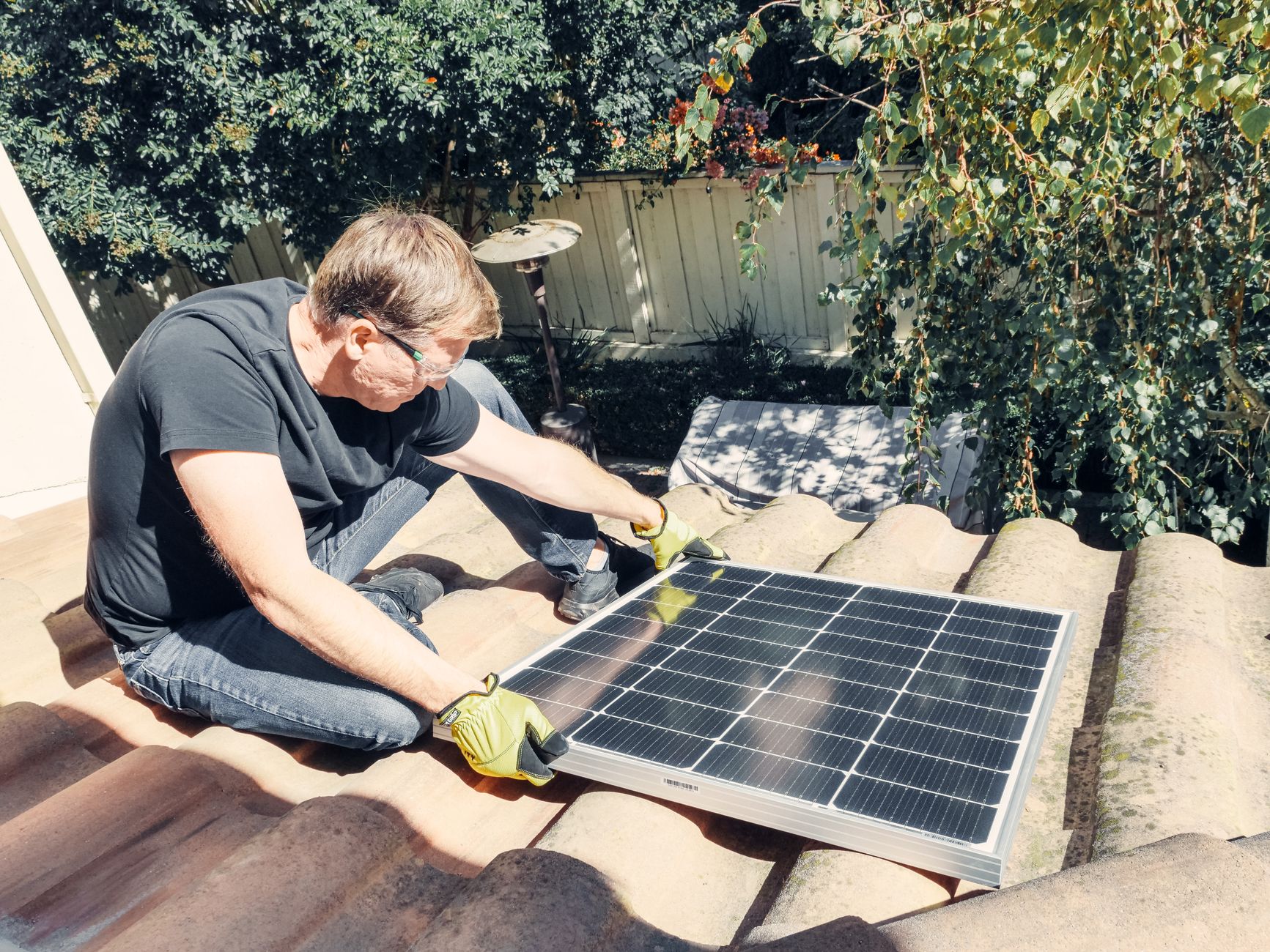 A skilled roofing technician from Santa Ana Roofing carefully inspecting the shingles on a residential roof in a tree-lined Cambridge neighborhood.